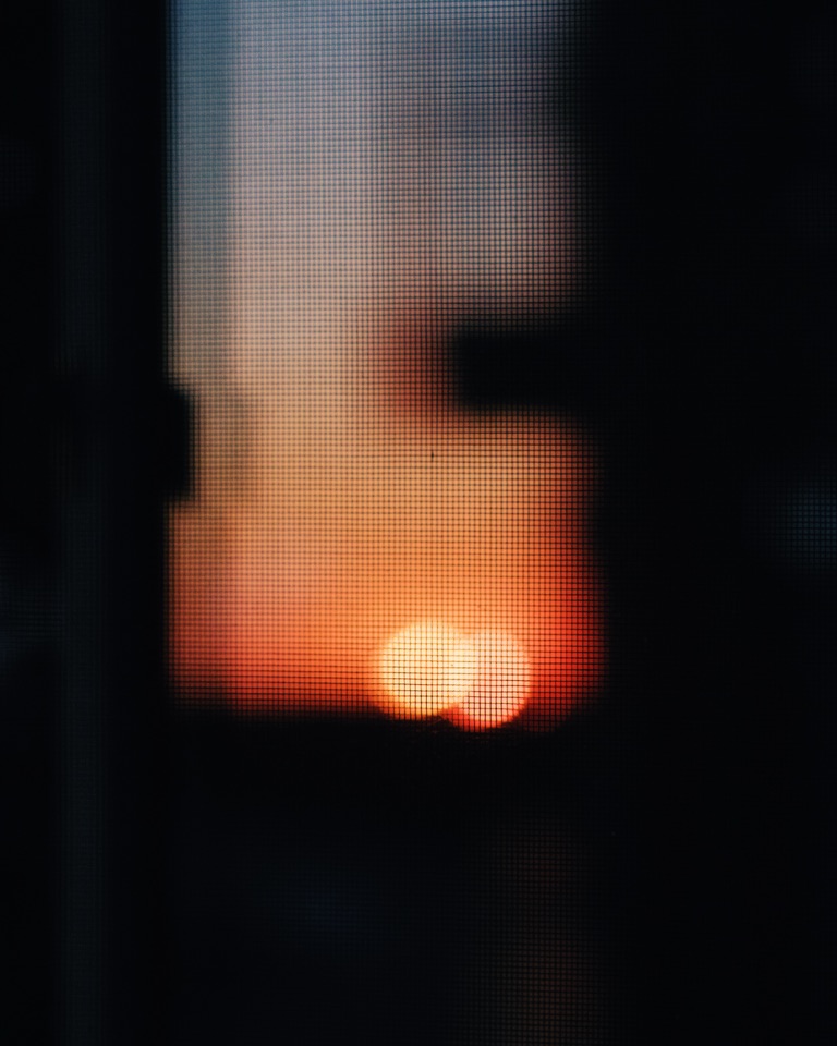 A sunset seen through a window screen