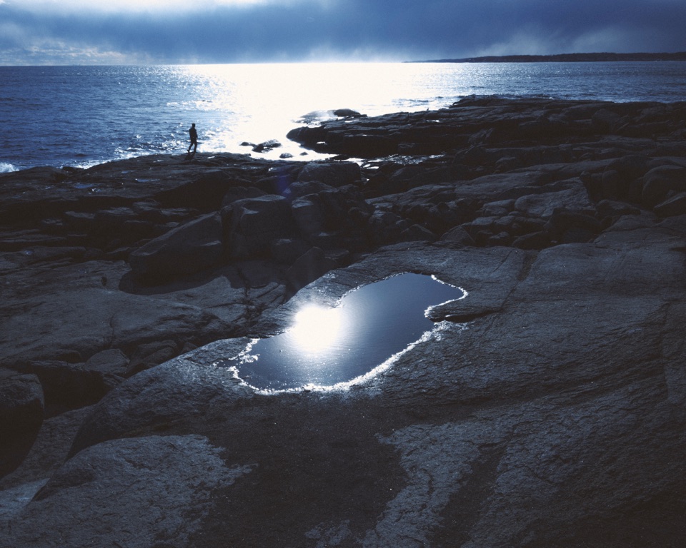 A tide pool on dark rocks reflecting the sky