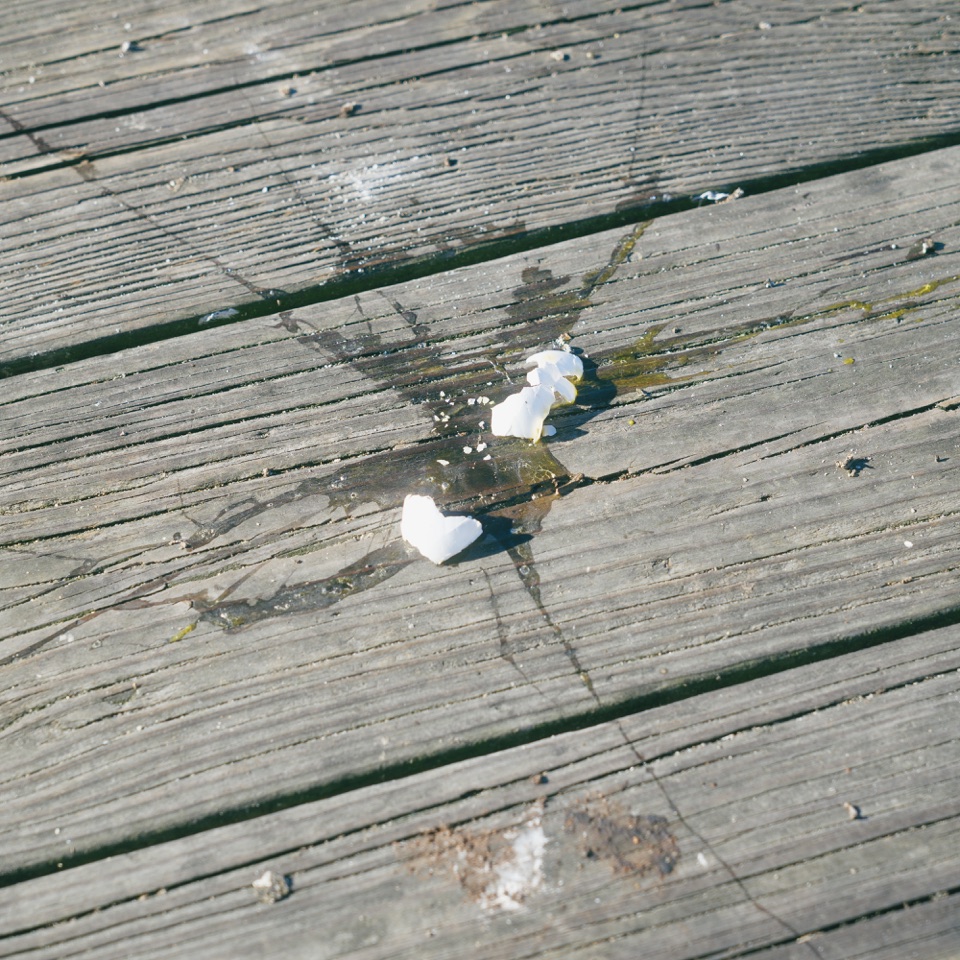 A broken egg on a wooden boardwalk