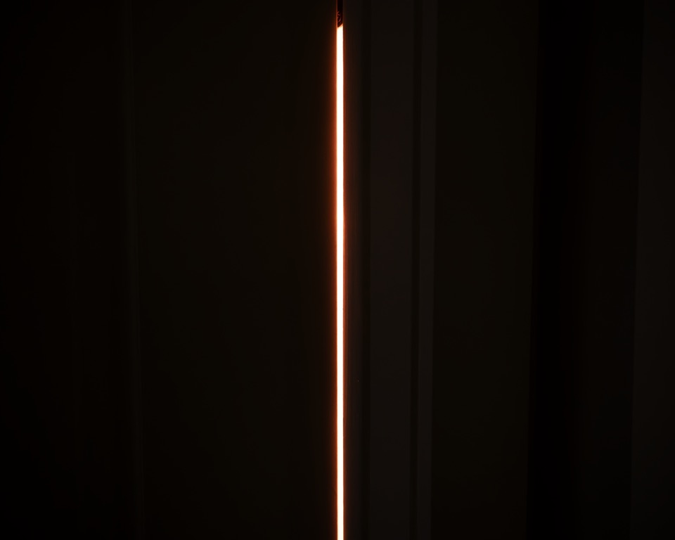 A thin line of light through a door left slightly open, at night